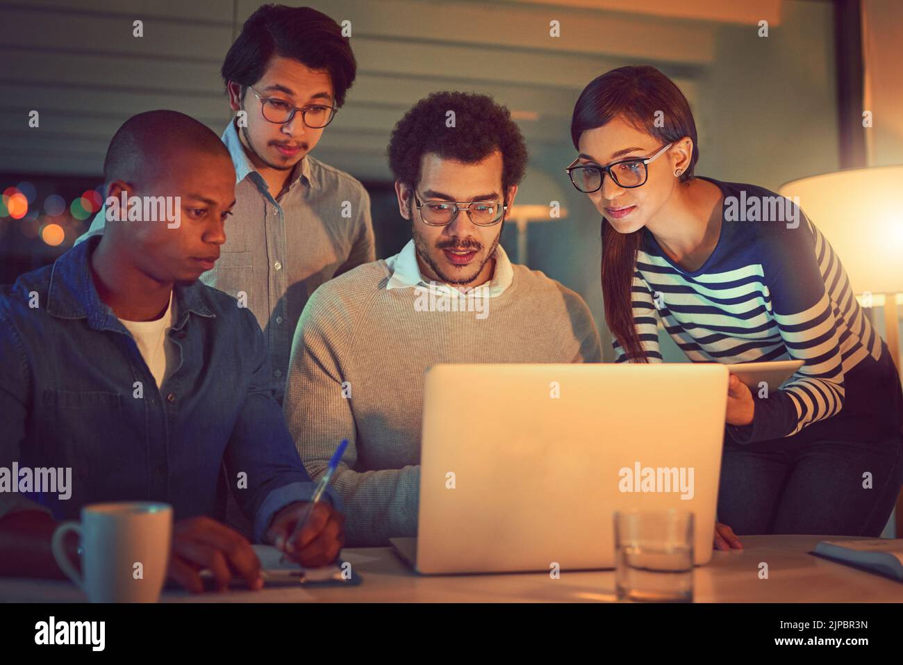 Putting their heads together to complete the project. a group of designers working late in an office. Stock Photo