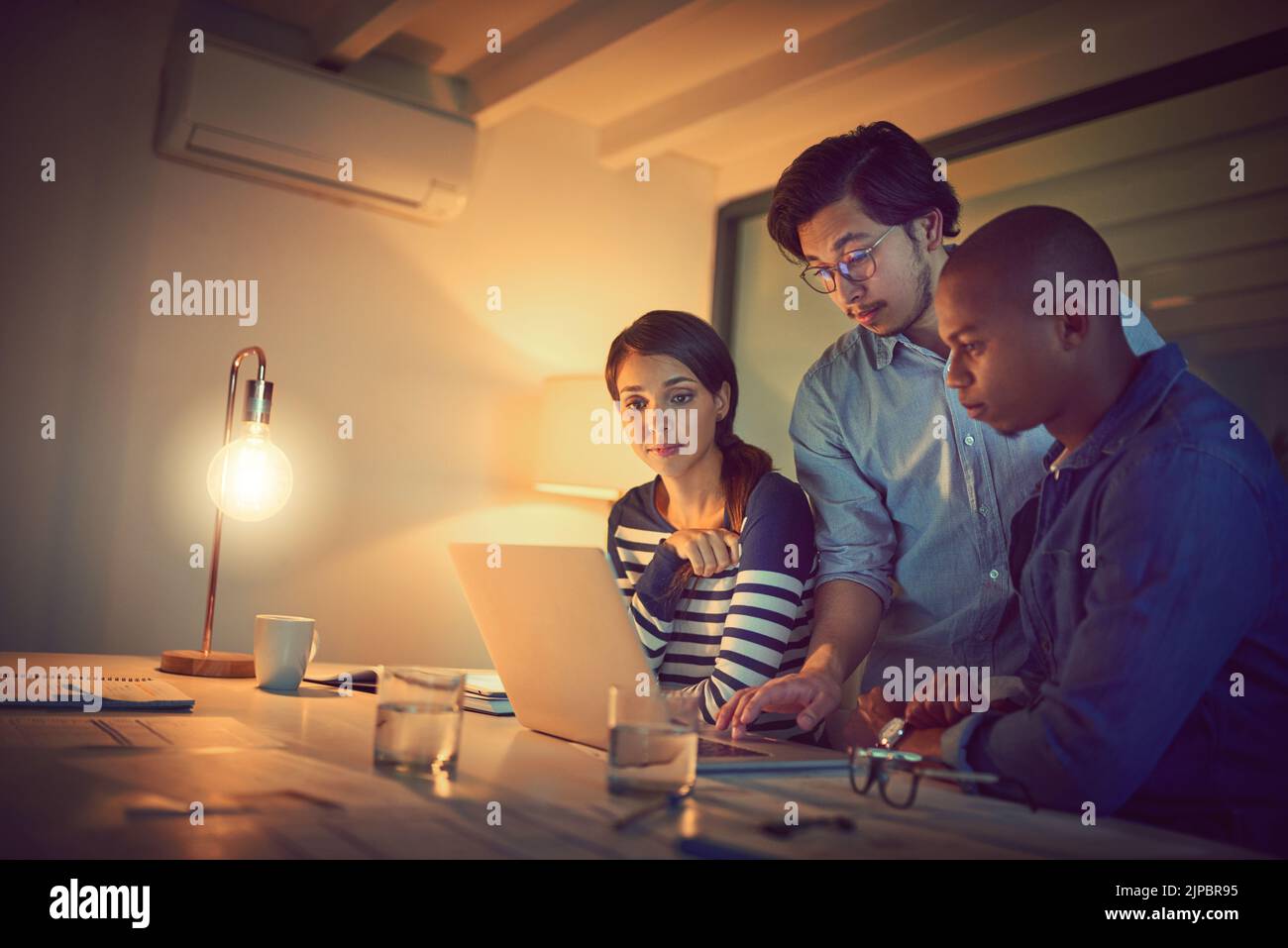 They have deadlines to meet. a group of designers working late in an office. Stock Photo