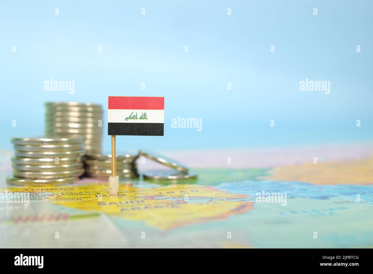 Selective focus of Iraqi flag in blurry world map with coins. Iraq economy and wealth concept. Stock Photo