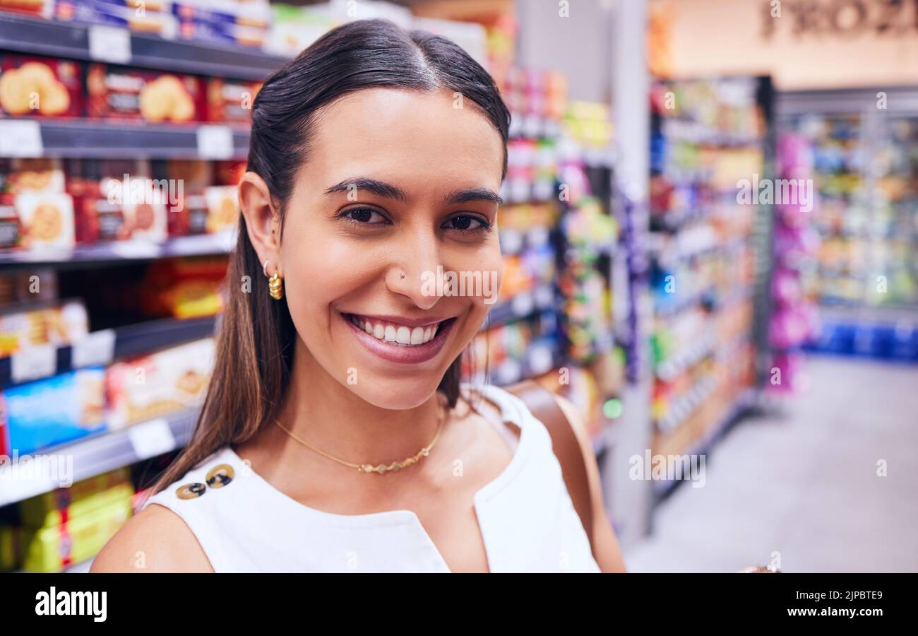 Shopping, groceries and consumerism with a young woman in a grocery store, retail shop or supermarket aisle. Closeup portrait of a female standing Stock Photo