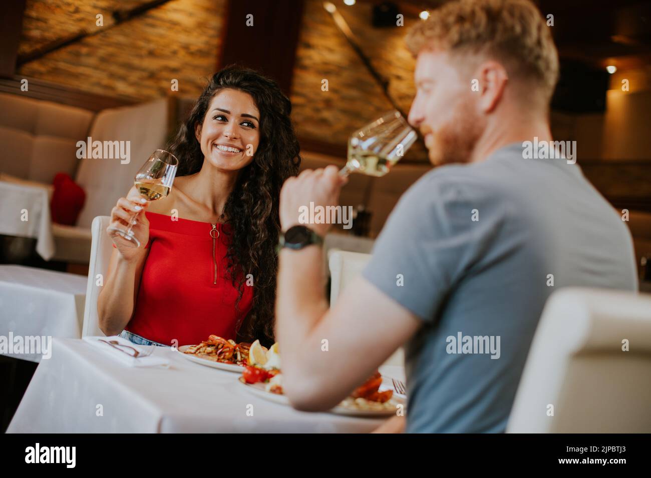 Handsome young couple having lunch with white wine in the restaurant Stock Photo