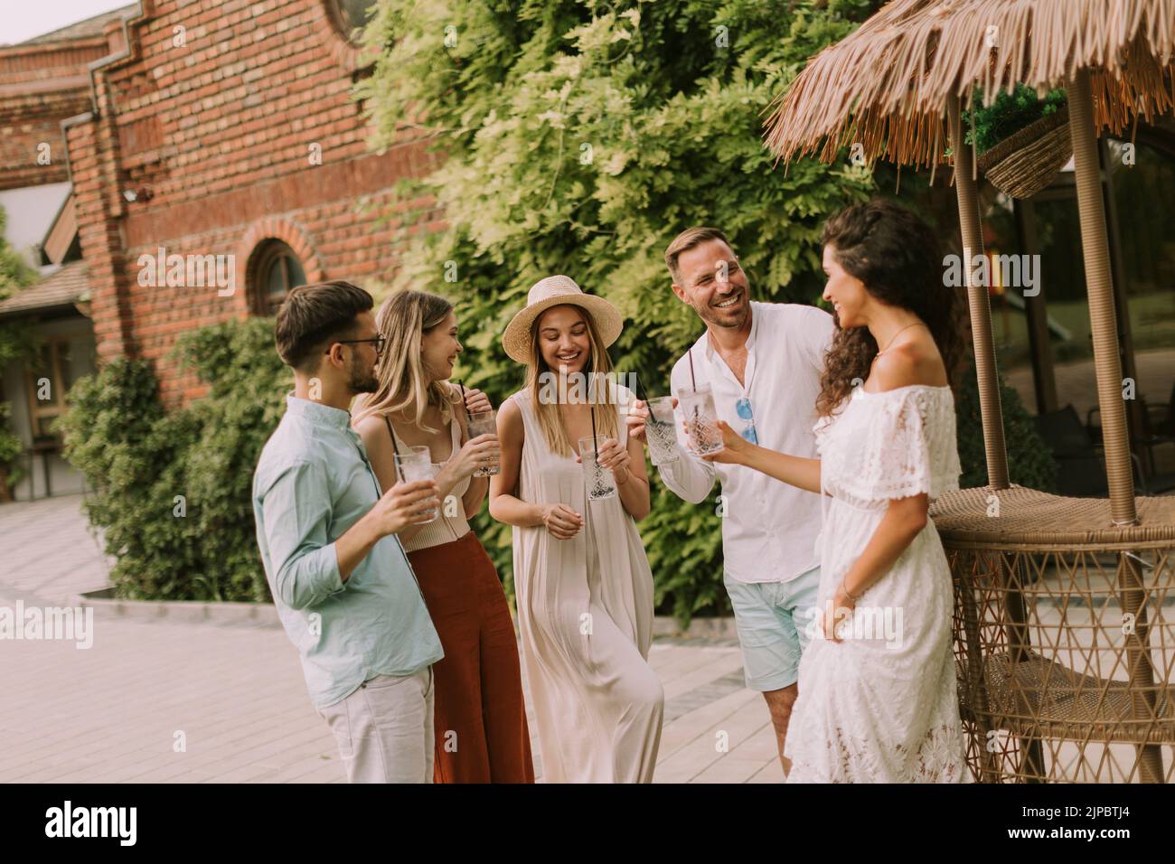 Group of happy young people cheering and having fun outdoors with drinks Stock Photo