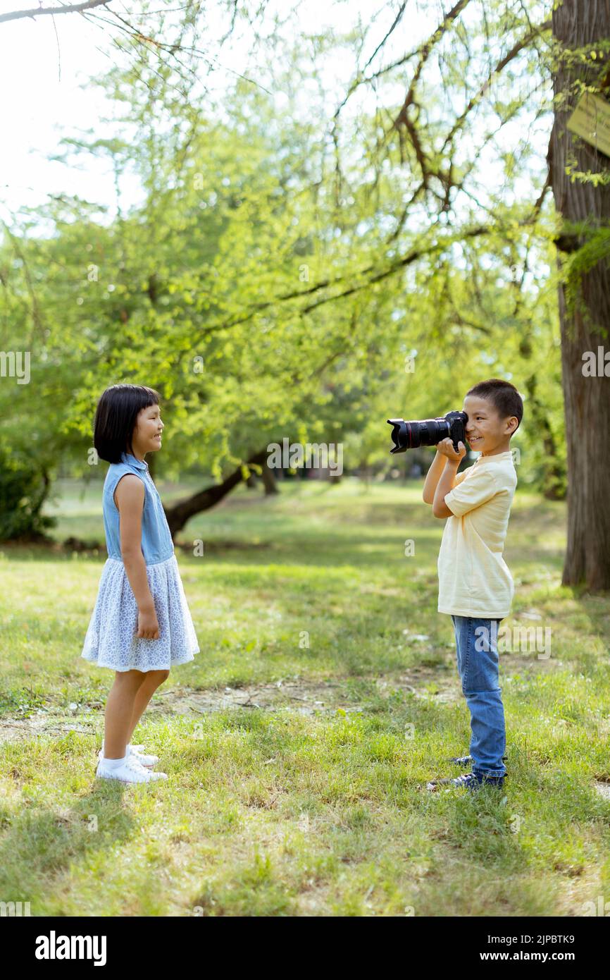 Cute little asian boy acting like a professional photographer while taking photos of his little sister Stock Photo