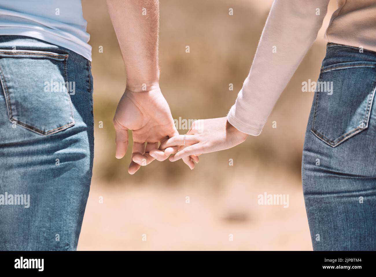 Affectionate couple holding hands showing love, caring and bonding outside together in nature. Loving boyfriend and girlfriend expressing unity Stock Photo