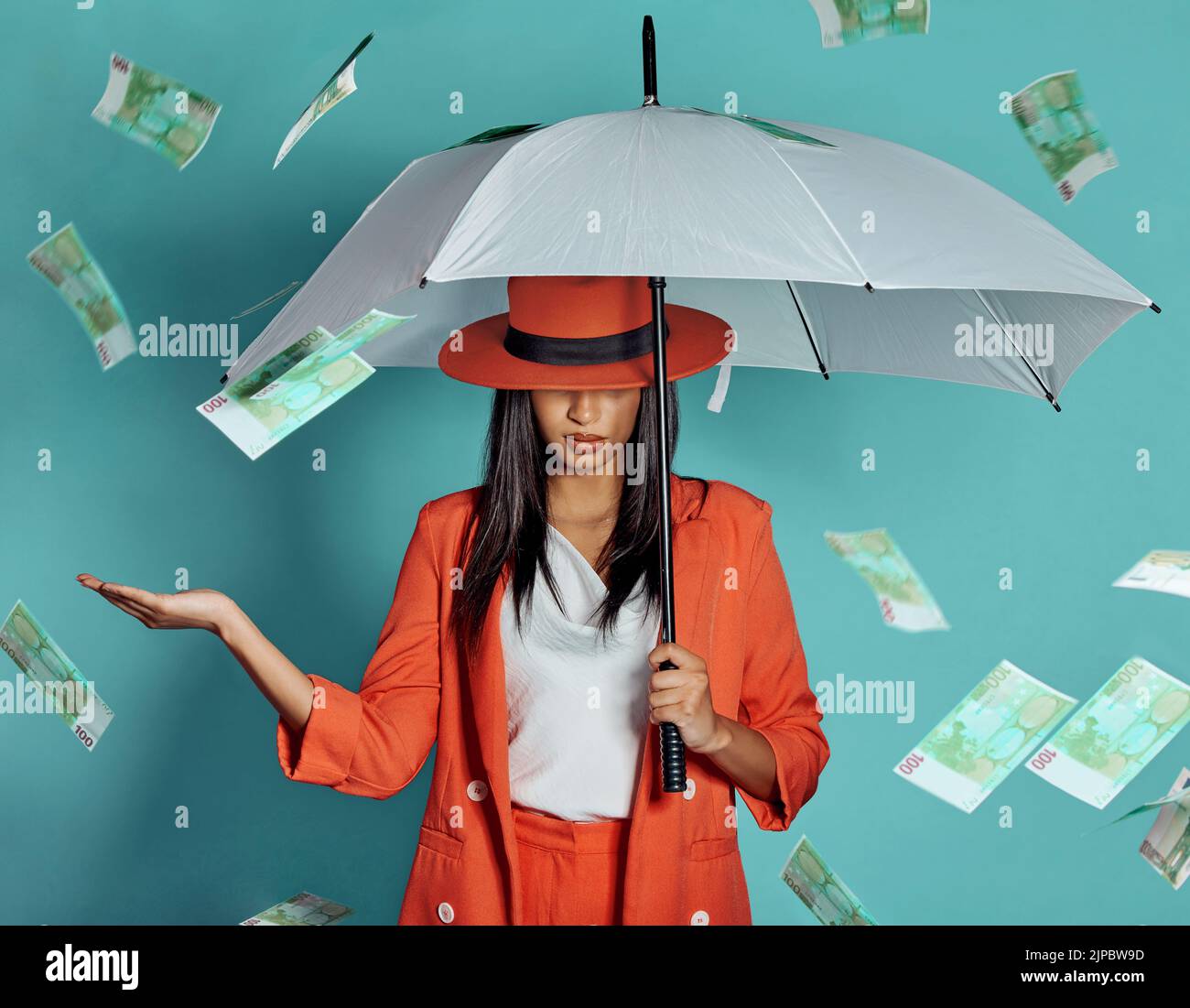 Money, fashion and rich lady being showered by cash while holding umbrella for insurance, protection and cover showing her wealth after payout Stock Photo