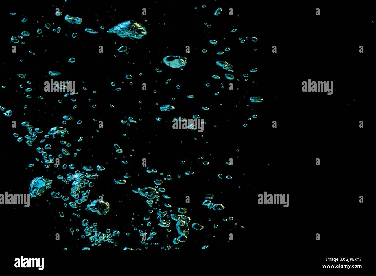 A bubble splash in transparent clear water yellow and blue light on a black nature background Stock Photo