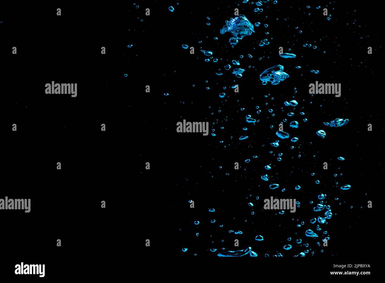 A bubble splash in transparent clear water liquid in blue light on a black nature background Stock Photo