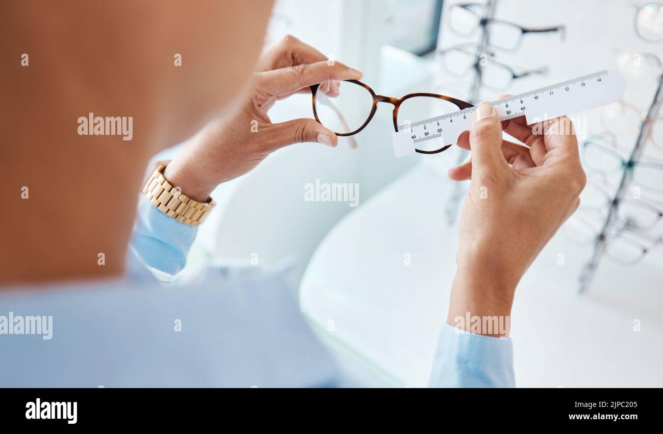 Optician or optometrist hands measuring and preparing pair of glasses and frame with optic ruler tool. Eye doctor or ophthalmologist determines visual Stock Photo
