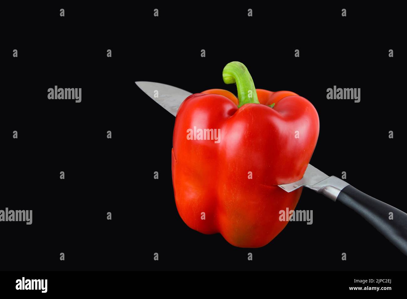 Knife cutting red pepper on wooden board Stock Photo