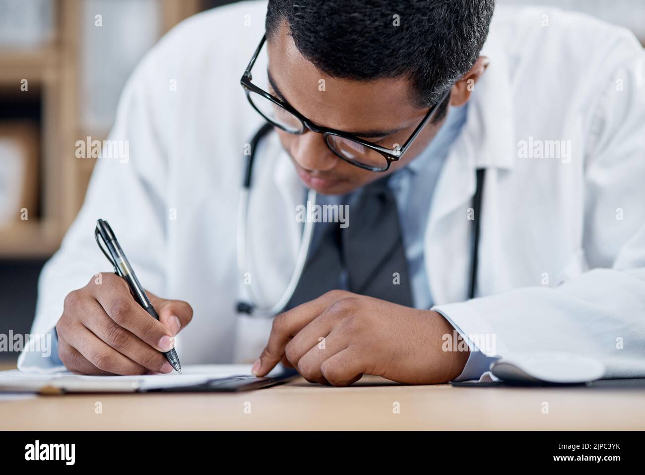 Doctor writing a prescription, survey or medical care paperwork for a patient at the hospital. A healthcare professional writing a patient information Stock Photo