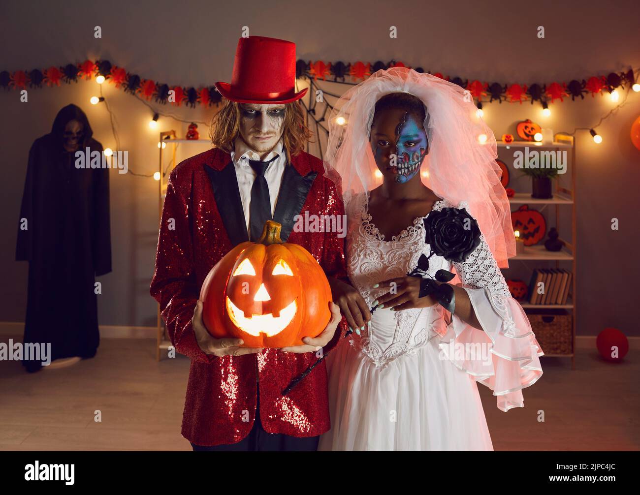Spooky Halloween portrait of creepy man and woman who are dressed as dead bride and joker. Stock Photo