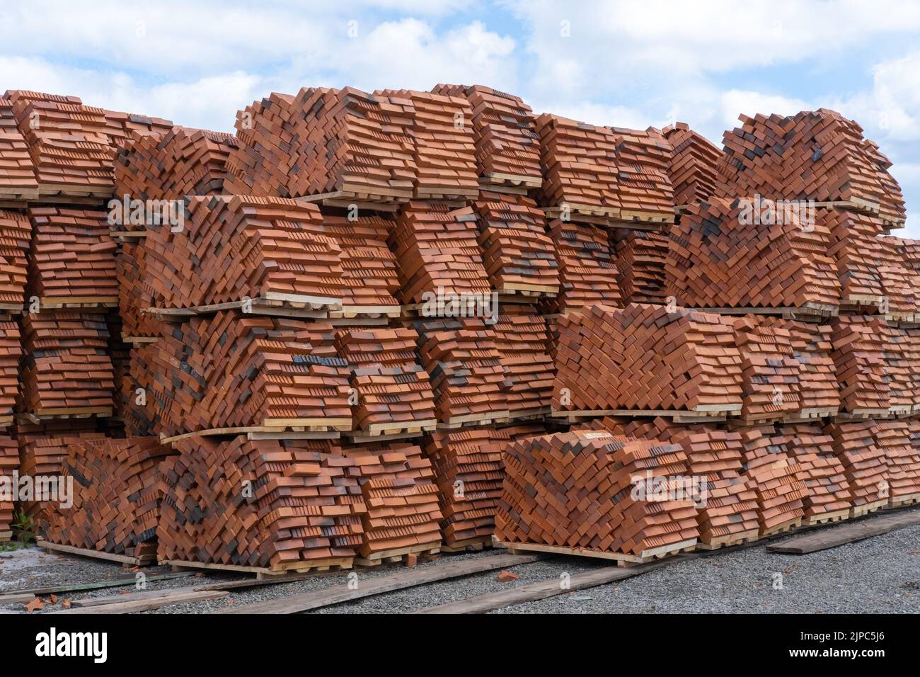 Red clay bricks are stacked on wooden pallets. Production of bricks from clay. Red perforated bricks with rectangular holes on wooden pallets in an op Stock Photo