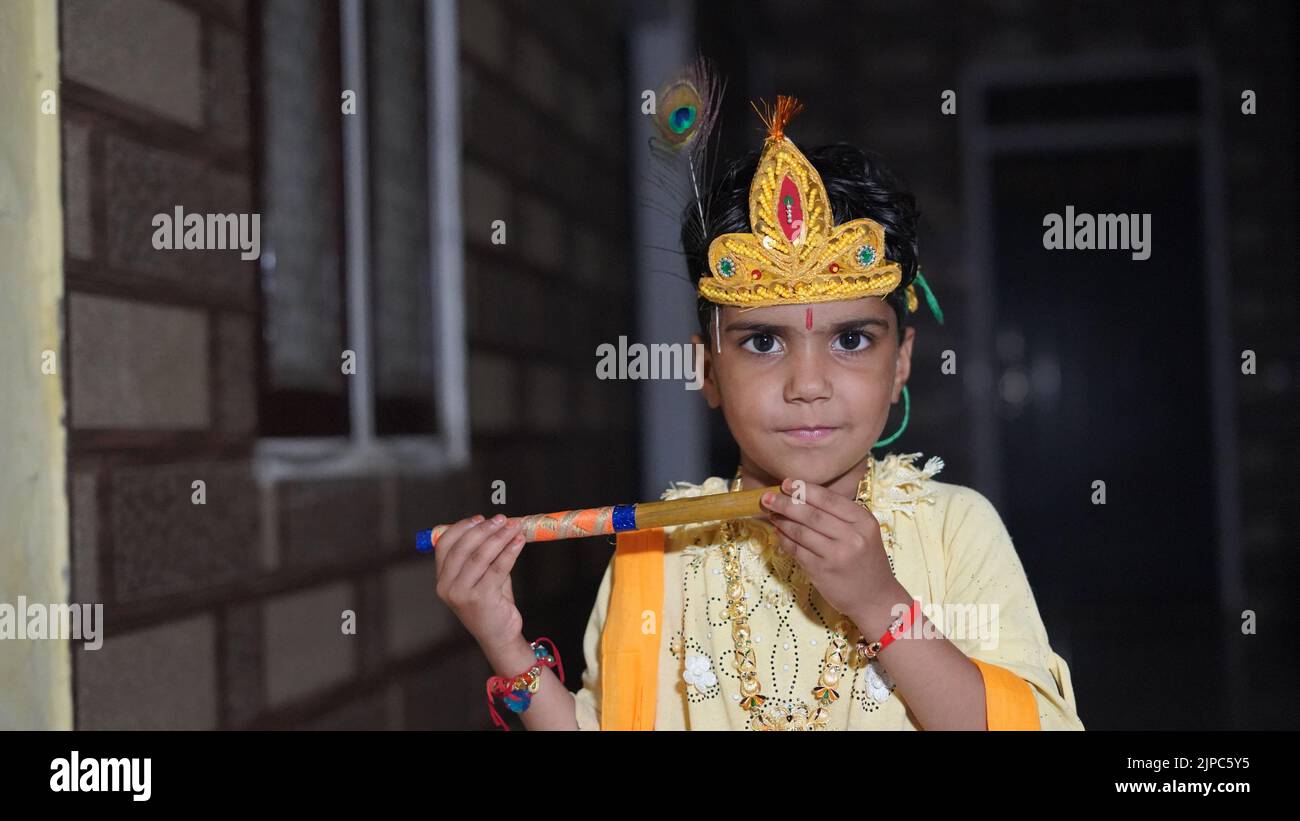 Indian Little child wearing Lord Krishna costume with flute or bansuri and celebration Janmashtami festival Stock Photo