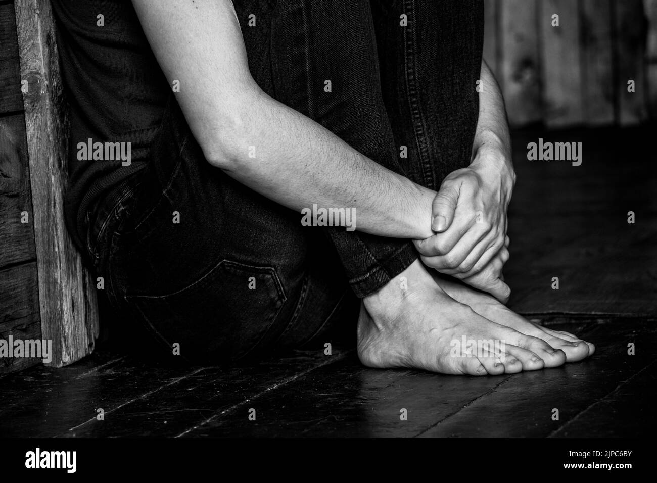 A Ukrainian girl sits on the floor in a corner and is afraid in the dark, fear and loneliness. The war in Ukraine, we mourn the dead Stock Photo