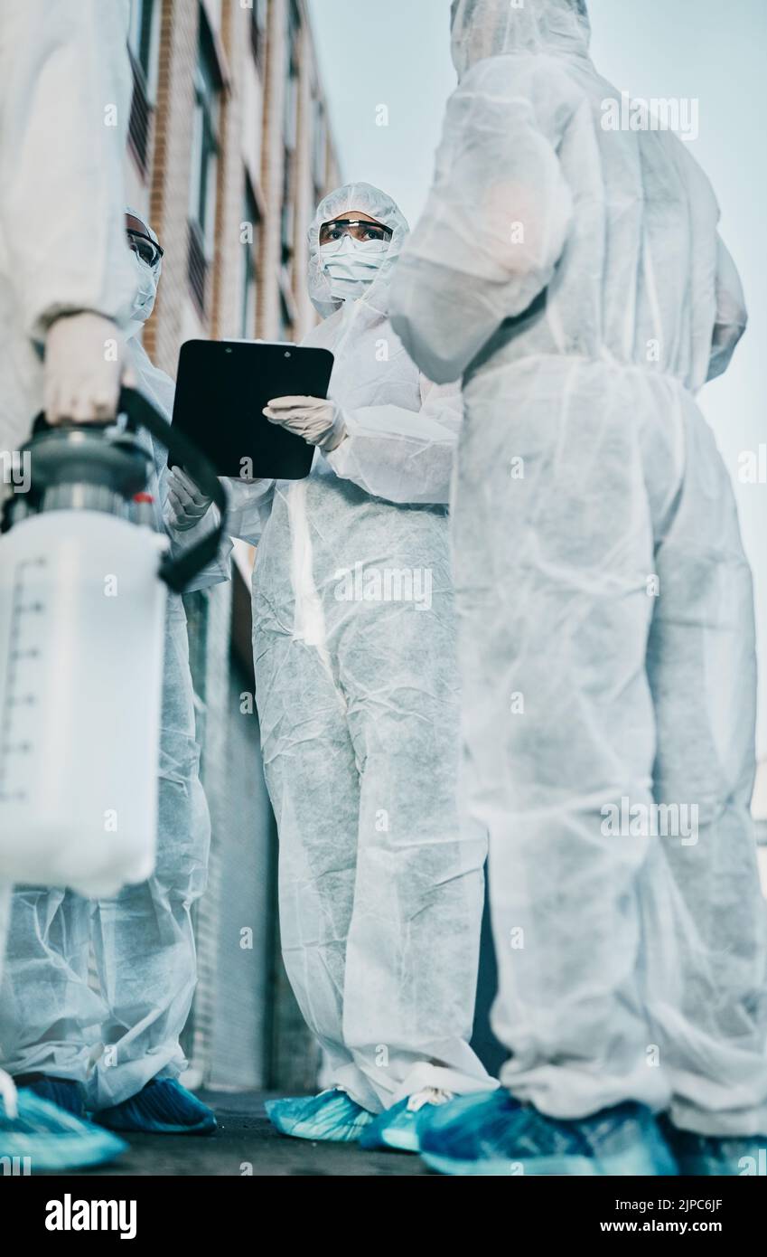Healthcare workers outside in protective gear during an outbreak in the city. A group of scientists wearing hazmat suits, cleaning urban areas. Safety Stock Photo