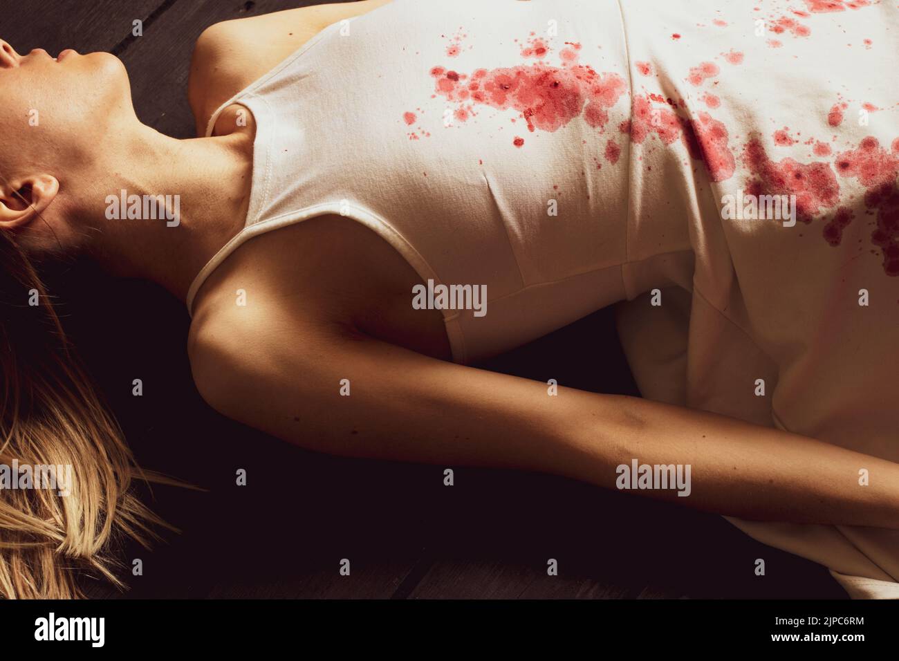A murdered and tortured Ukrainian woman in a white dress and bloodstains lies on the floor of the house, a protest action of Ukrainian women Stock Photo