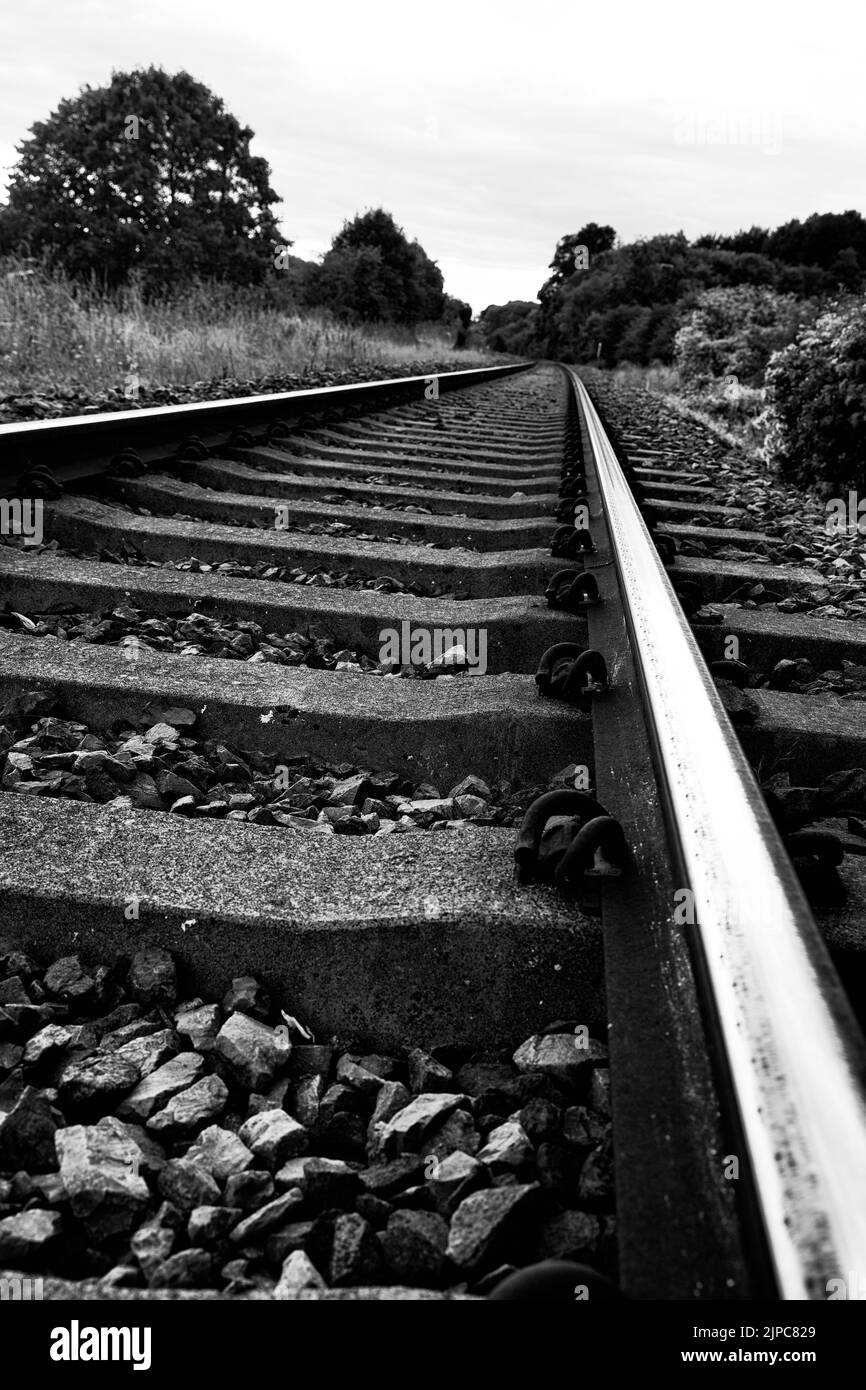 A grayscale closeup of railway track around the tiny rural train station at Combe, Oxfordshire Stock Photo