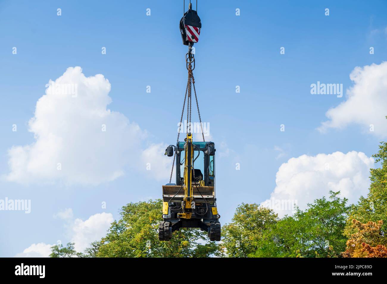 A small excavator is lifted with a crane Stock Photo