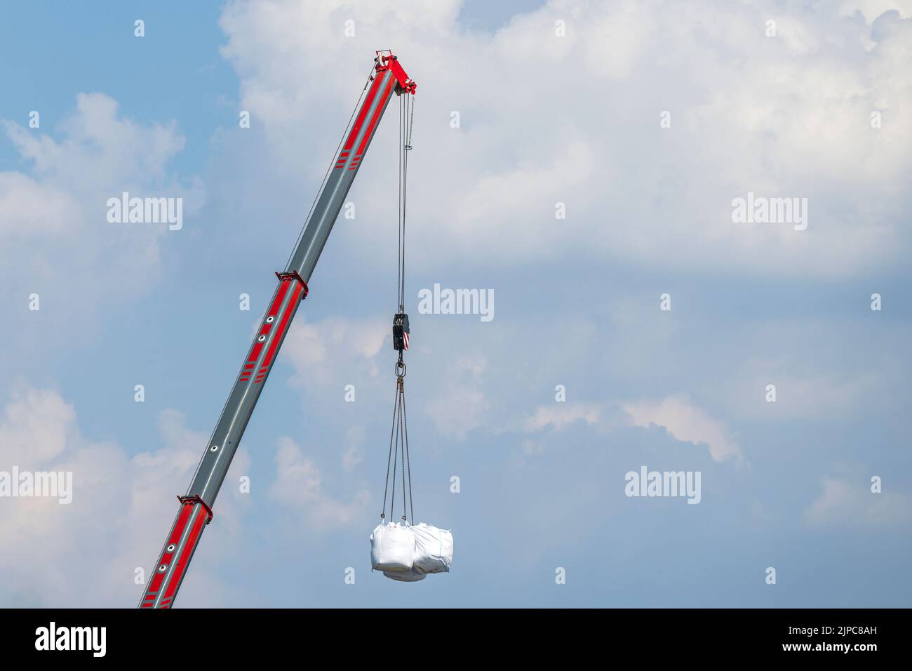 Several transport bags hang on the hook of a crane Stock Photo