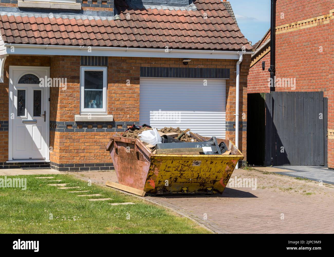 Rubbish skip on front drive awaiting collection Stock Photo