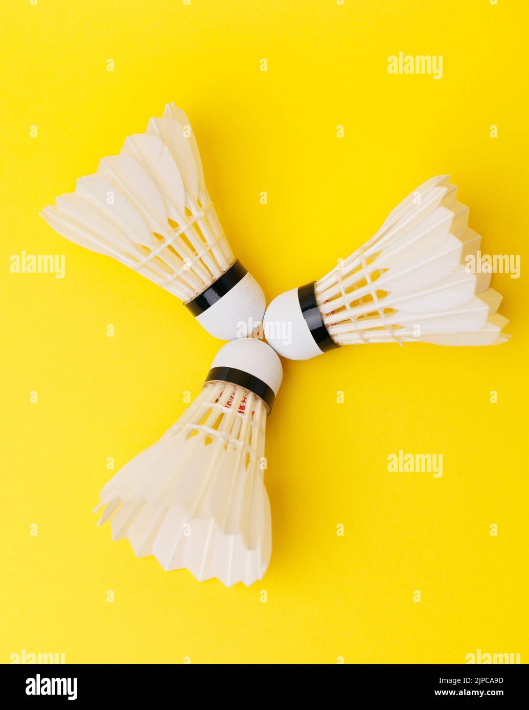 Three real feather badminton shuttlecocks isolated on the yellow