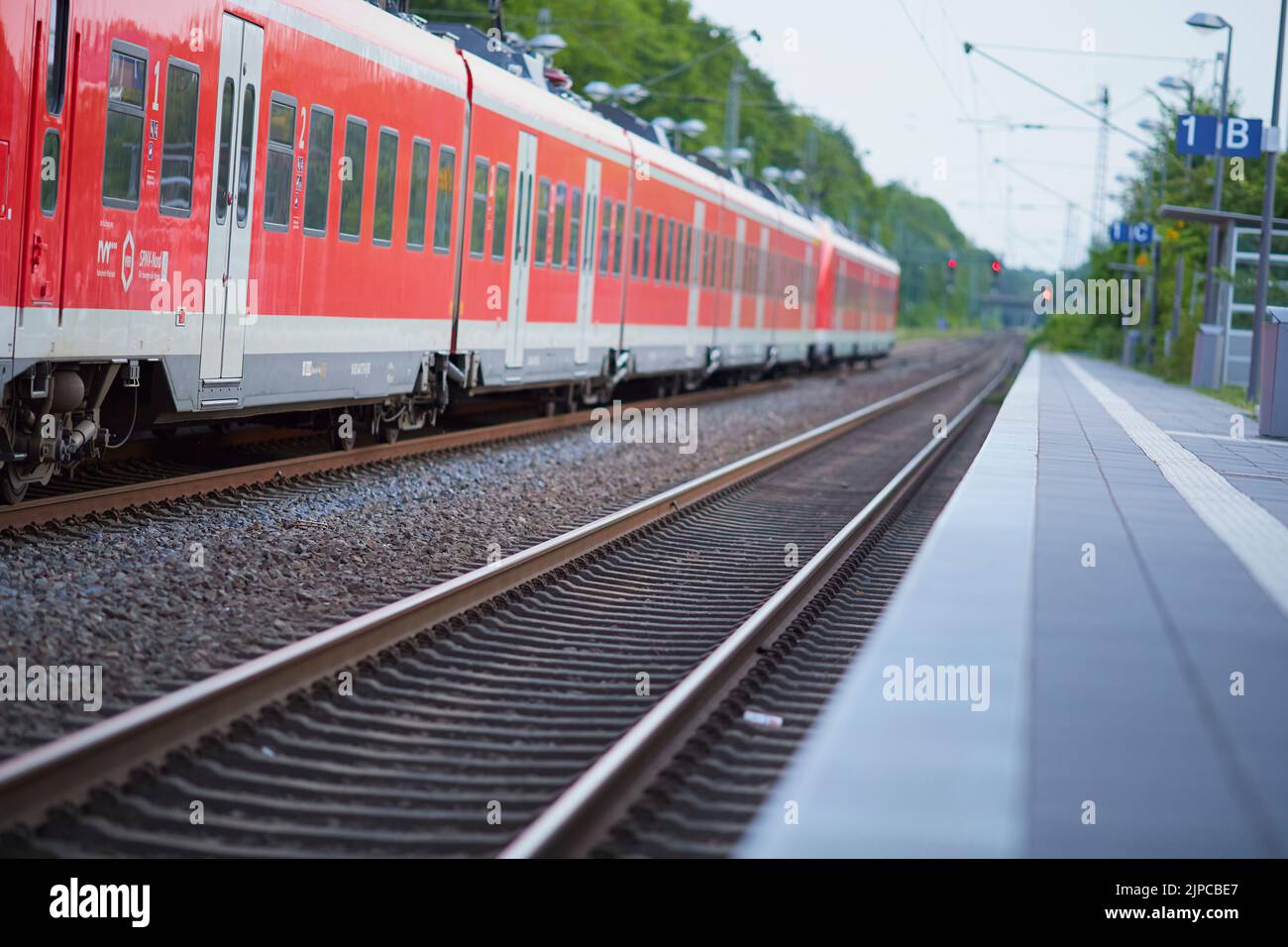 A red DB train arriving at a station in Geilenkirchen, Germany Stock Photo