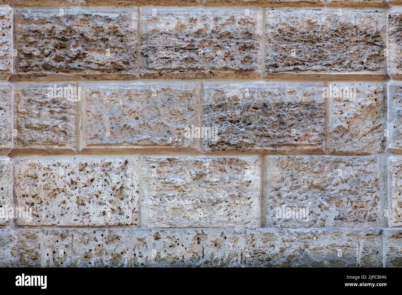 Background image - a fragment of the wall of an ancient building made of volcanic rocks. Stock Photo