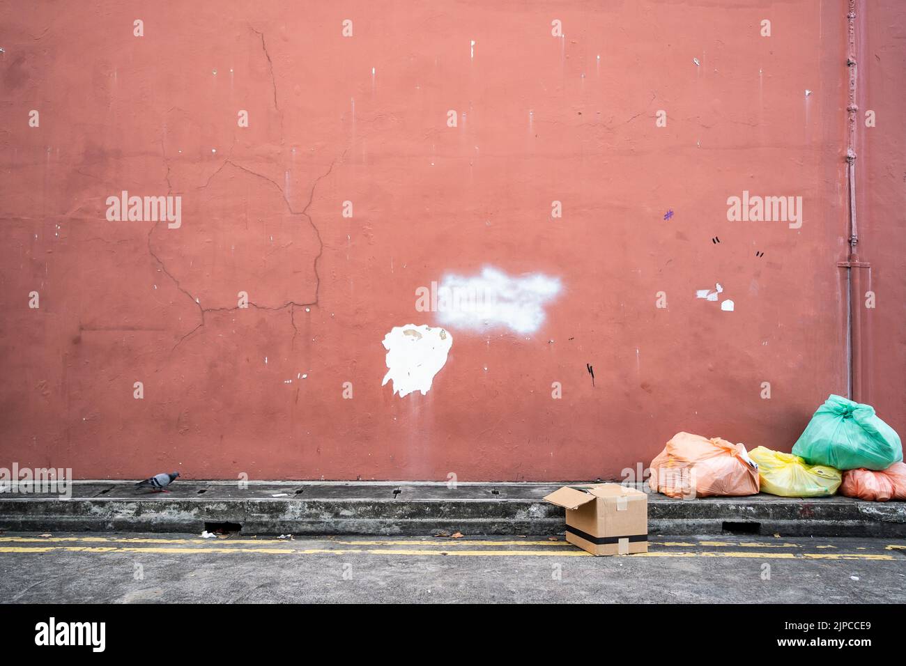 Old red wall with garbage bag Stock Photo