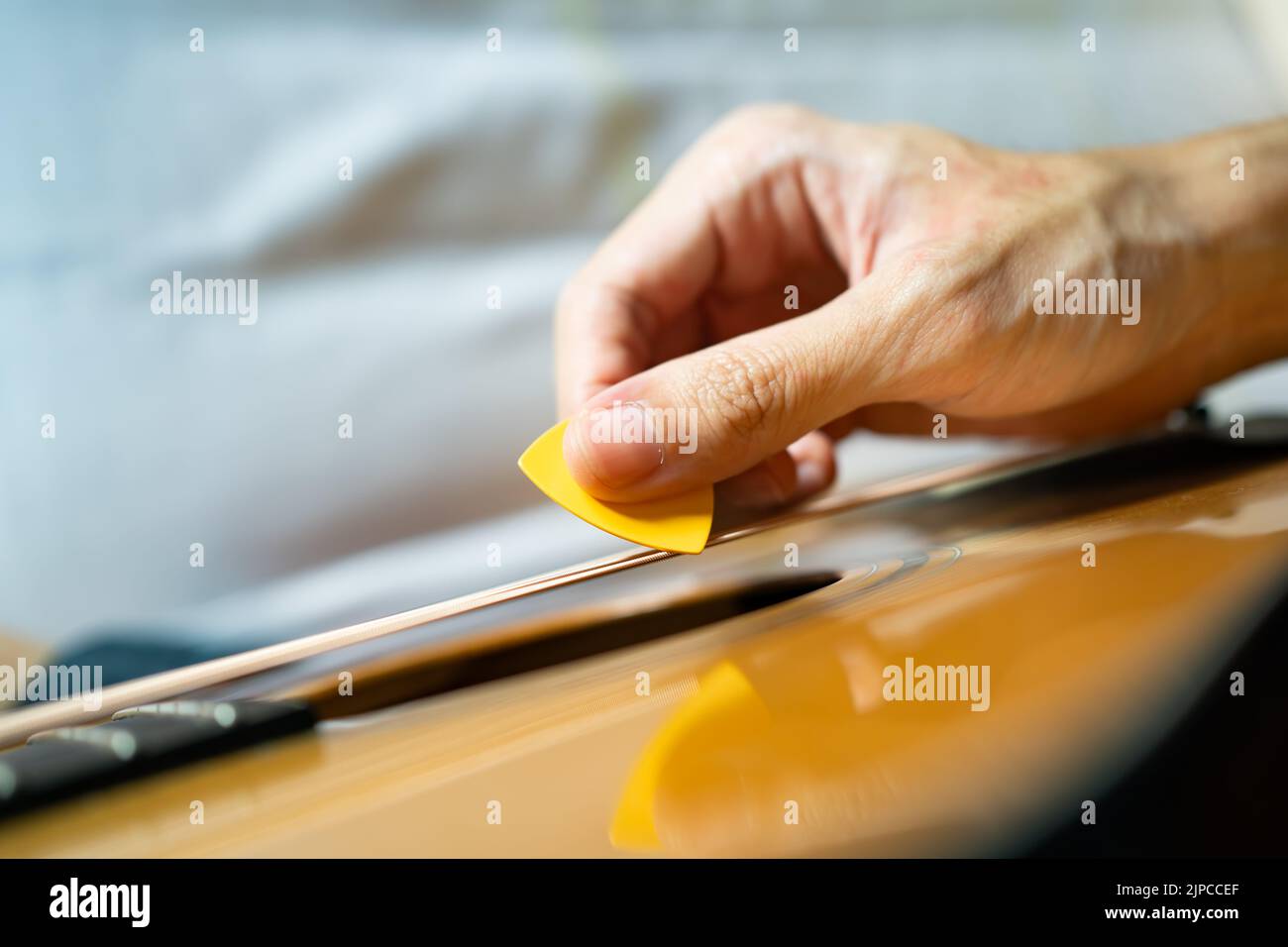 Guitarist playing acoustic guitar with a guitar pick Stock Photo