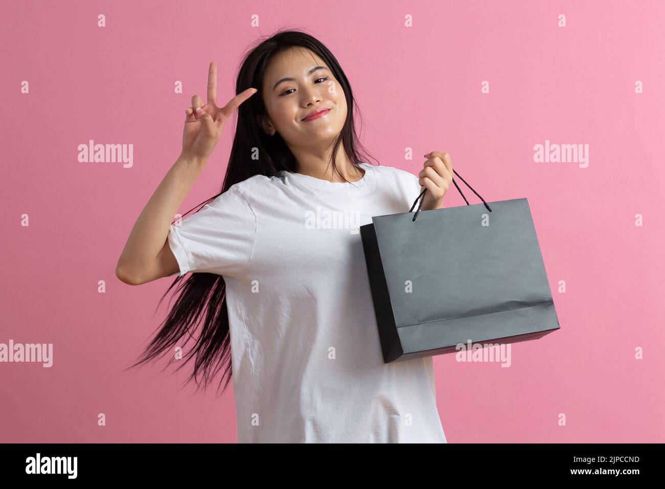 Shopping asian happy woman holding shopping bags on pink background. Stock Photo