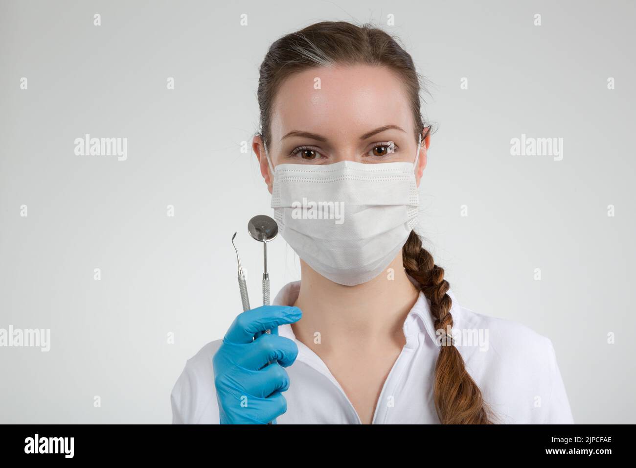 dentist's assistant /female dentist with dental face mask holds/shows