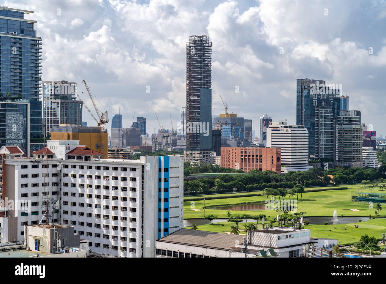 Bangkok, Thailand - 13 August 2022 - Aerial view of Bangkok cityscape in the morning showing high-rises with a golf course and cloudy blue sky Stock Photo