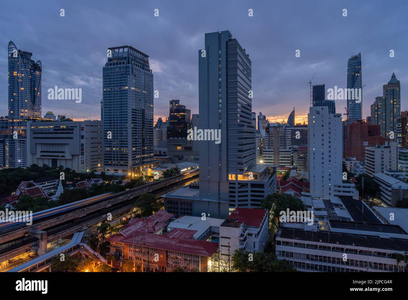 Bangkok, Thailand - 12 August 2022 - Aerial view of Bangkok cityscape in the morning before sunrise showing high-rises and running BTS skytrains and c Stock Photo