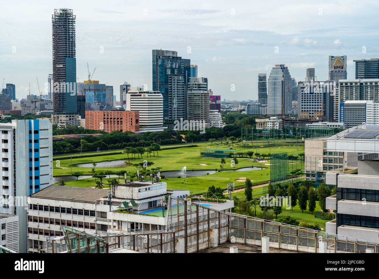 Bangkok, Thailand - 11 August 2022 - Aerial view of Bangkok cityscape in the morning showing high-rises with a golf course and cloudy blue sky Stock Photo