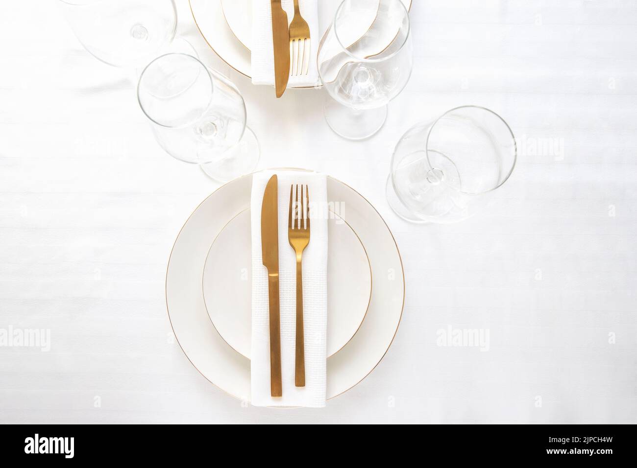 Top view of tableware with linen napkins, gold cutlery and white