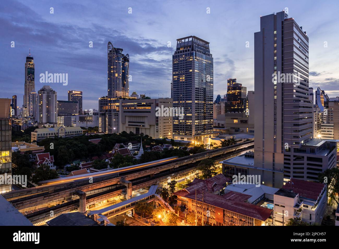 Bangkok, Thailand - 11 August 2022 - Aerial view of Bangkok cityscape in the morning before sunrise showing high-rises and running BTS skytrains and c Stock Photo