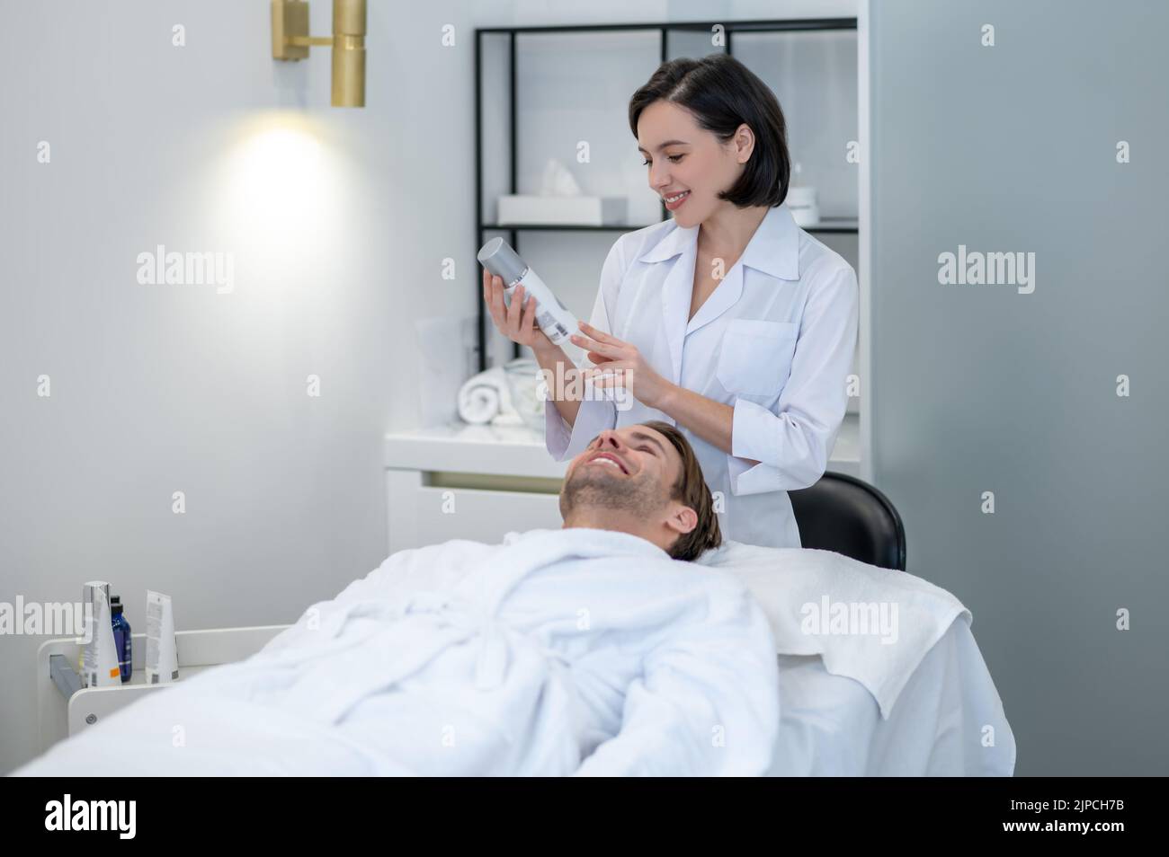 Young woman in lab coat working with a customer in a beauty salon Stock ...