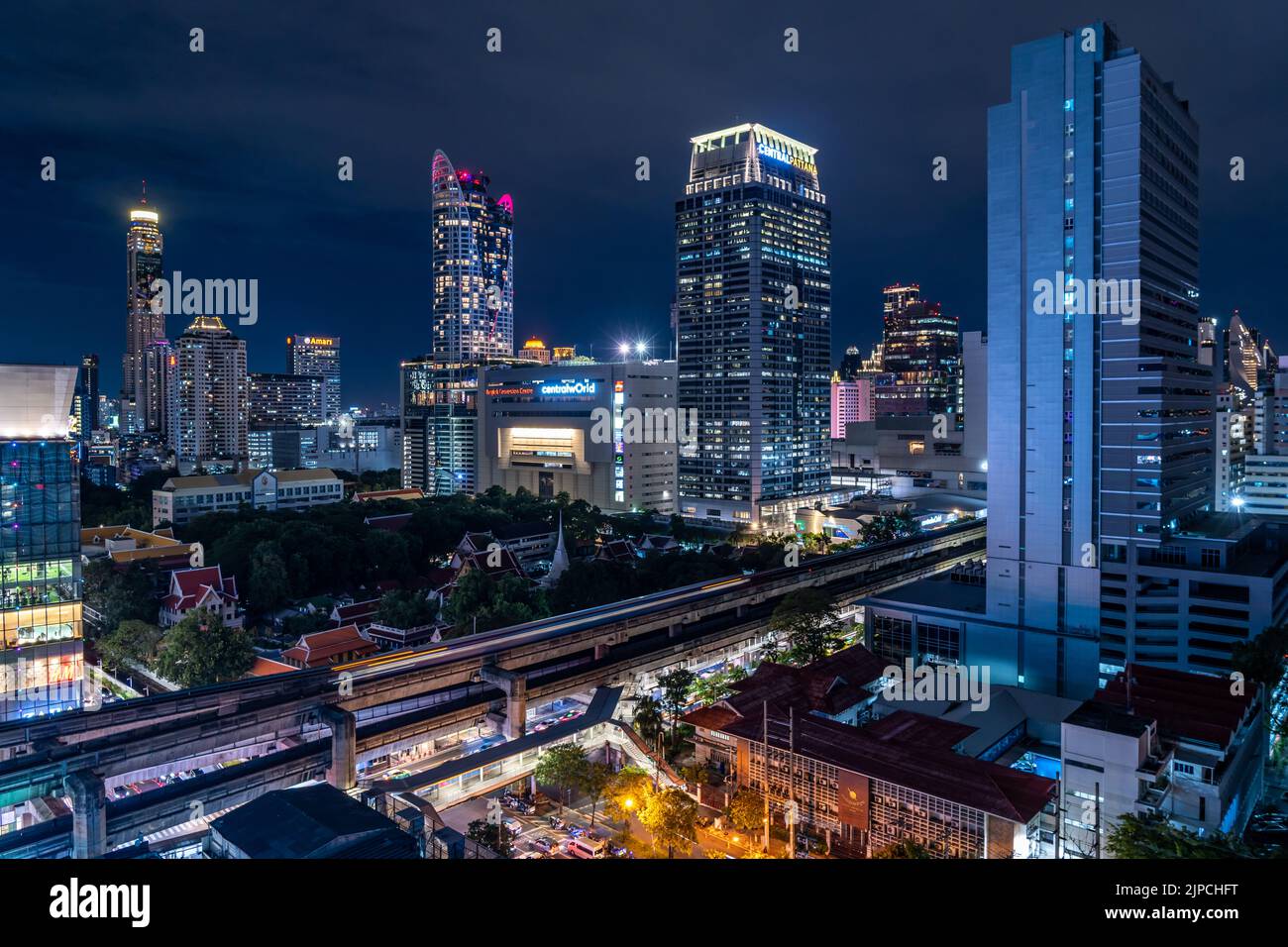 Bangkok, Thailand - 10 August 2022 - Aerial view of Bangkok cityscape at night after sunset showing high-rises and running BTS skytrains Stock Photo