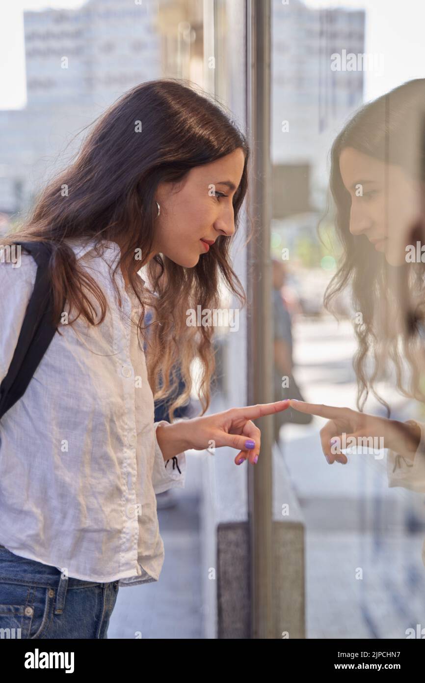 Close-up portrait of a young woman looking in a shop window Stock Photo