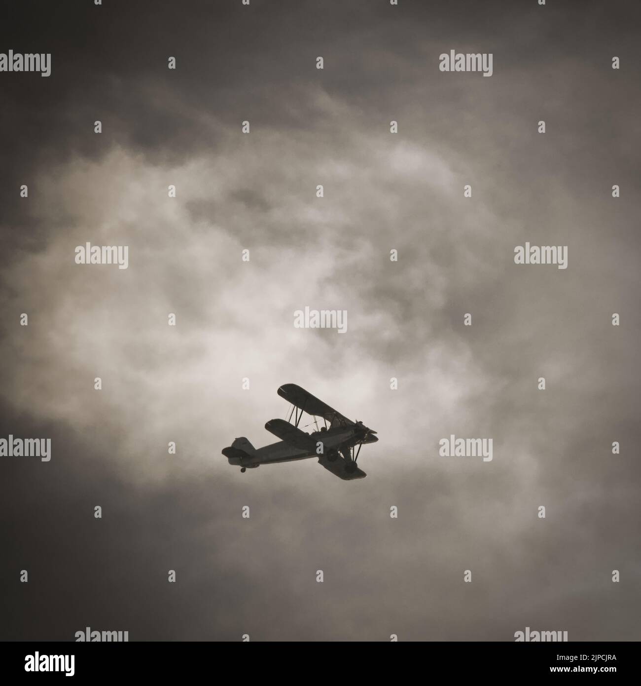 A retro airplane flying under cloudy sky Stock Photo - Alamy