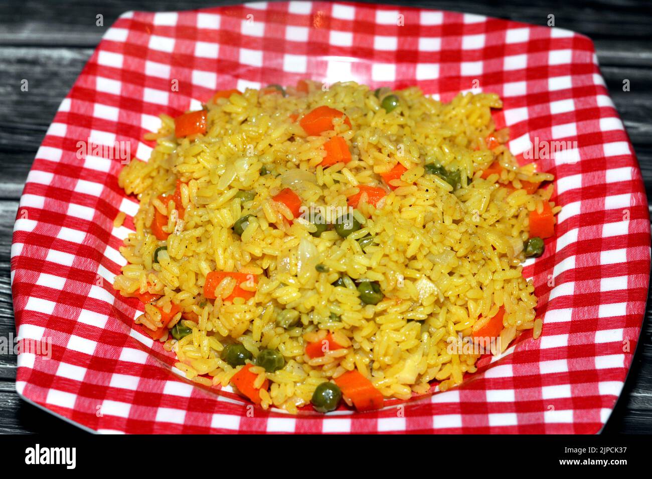 A plate of hot steamed long grain yellow Basmati rice with vegetables