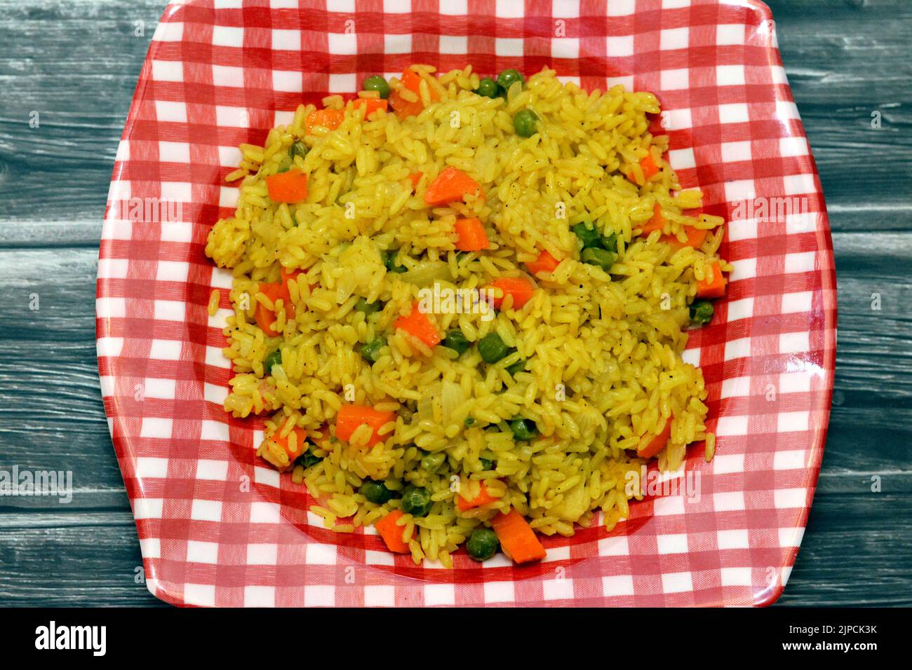 A plate of hot steamed long grain yellow Basmati rice with vegetables