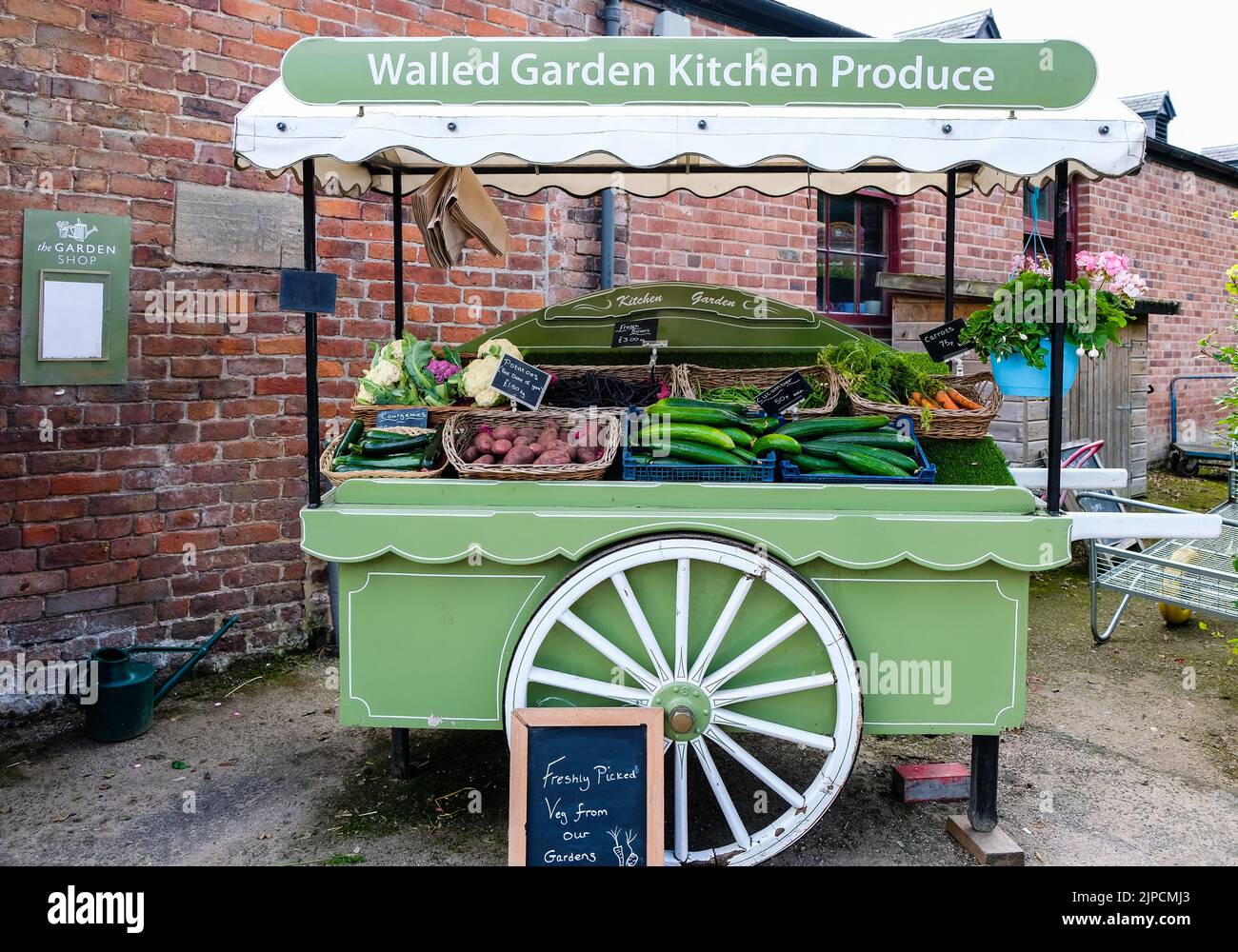 Freshly picked vegetables for sale outdoors on green wheel barrow,Walled Garden Kitchen Produce,Cauliflower,Courgettes,Carrots,Potatoes,Green Beans Stock Photo