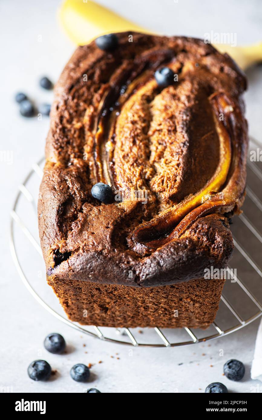 Banana bread with blueberries on a cooling rack on a gray background. Stock Photo