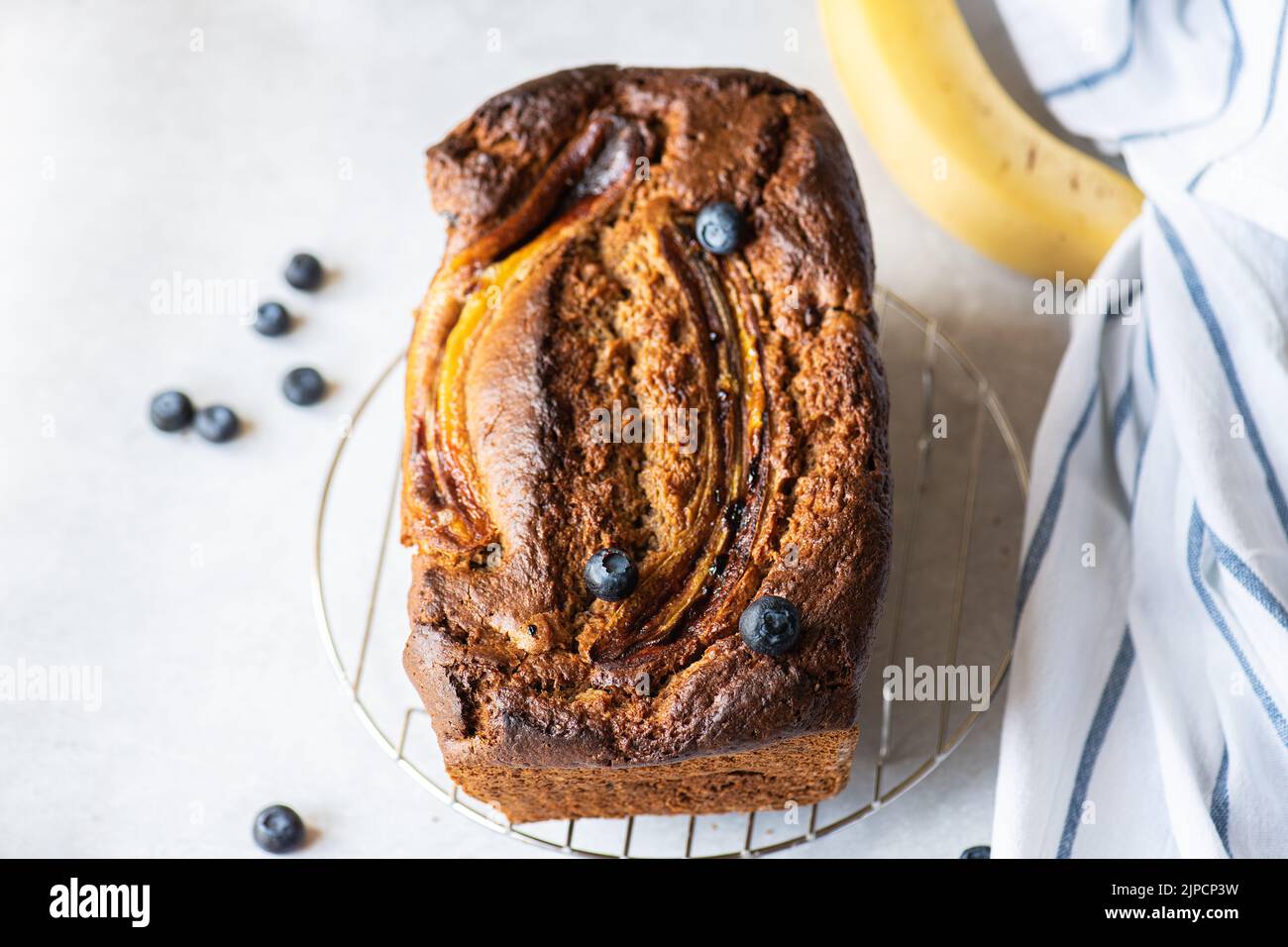 Banana bread with blueberries on a cooling rack on a gray background. Overhead view. Stock Photo