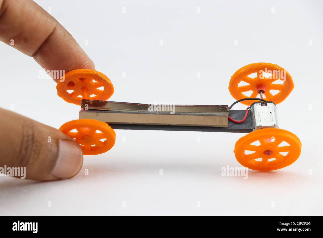 Mini solar car held in hand with wheels made from 3d printing technology. Future of 3d print technology shown with useful objects Stock Photo