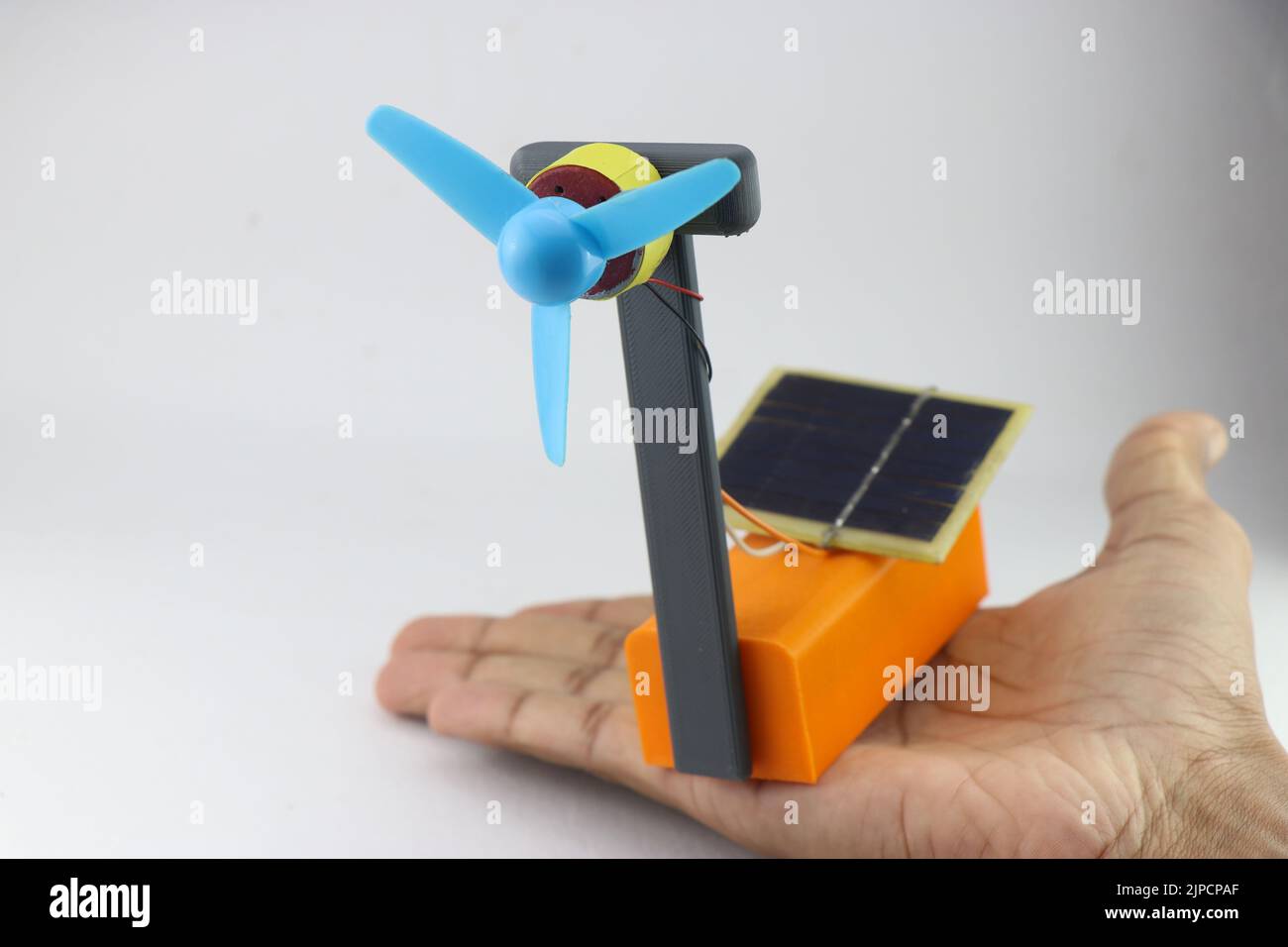 Solar energy absorbing solar panels that power small fan connected to a dc motor held in hand Stock Photo