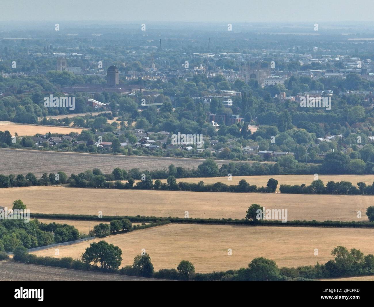 Cambridge, UK. 16th Aug, 2022. A haze hangs over the city of Cambridge, including the Cambridge library and Kings College behind golden fields. Although many parts of the country are starting to see heavy rain, it hasn't hit Cambridgeshire in any significant amount, and there is currently no hosepipe ban in the Anglian Water area, Peterborough, Cambridgeshire, UK, on August 16, 2022 Credit: Paul Marriott/Alamy Live News Stock Photo