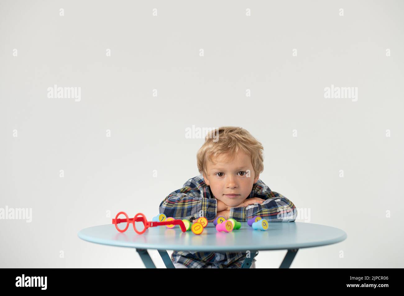 Boy sitting at a table, showing lotto number, school grade Stock Photo