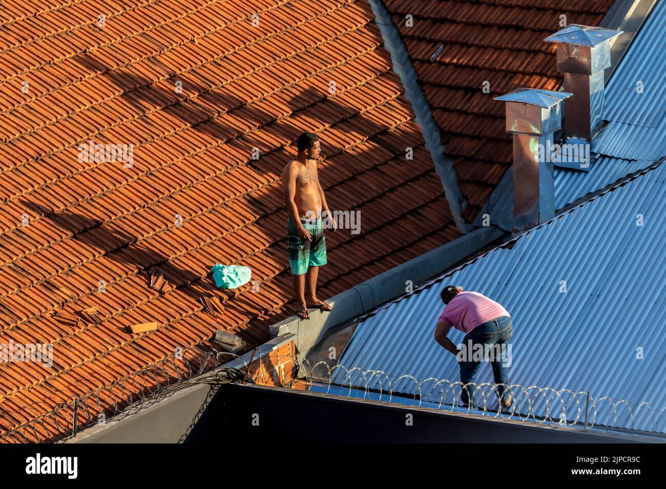 Marilia, Sao Paulo, Brazil, July 29, 2022. Top view of a worker placing metal sheets on a house to renovate the roof of a commercial point in the city Stock Photo